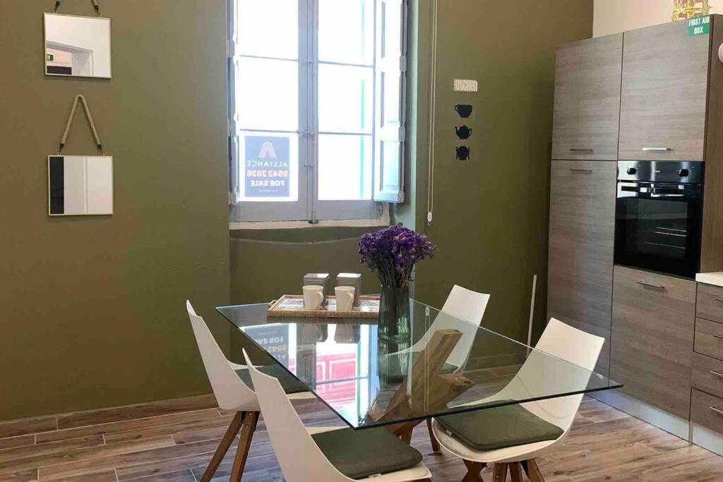 a dining room with a glass table and white chairs at Sliema - 2 mins from the Beach in Sliema