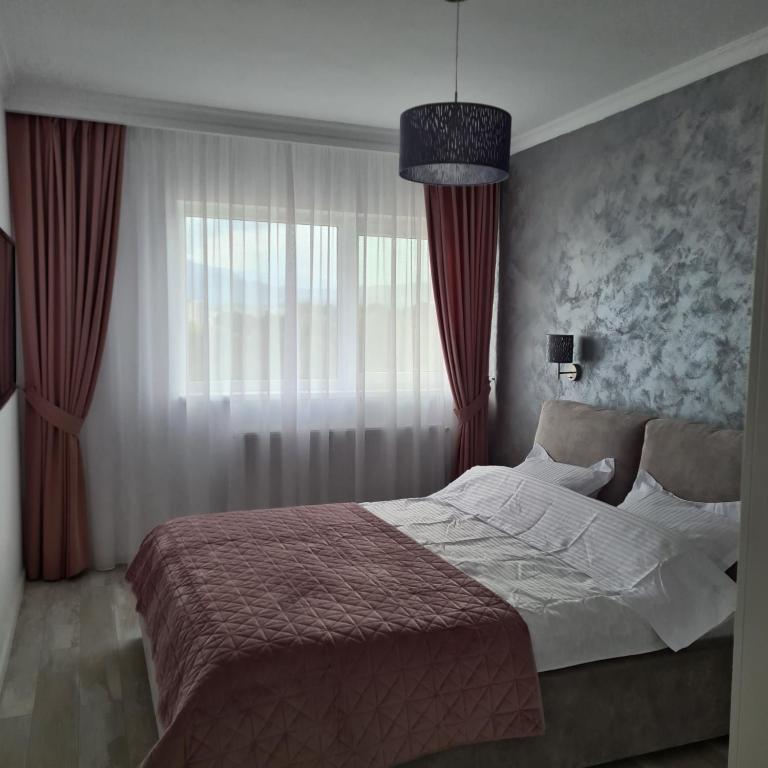 - une chambre avec un lit et une fenêtre avec des rideaux rouges dans l'établissement Panoramic Apartment, à Braşov