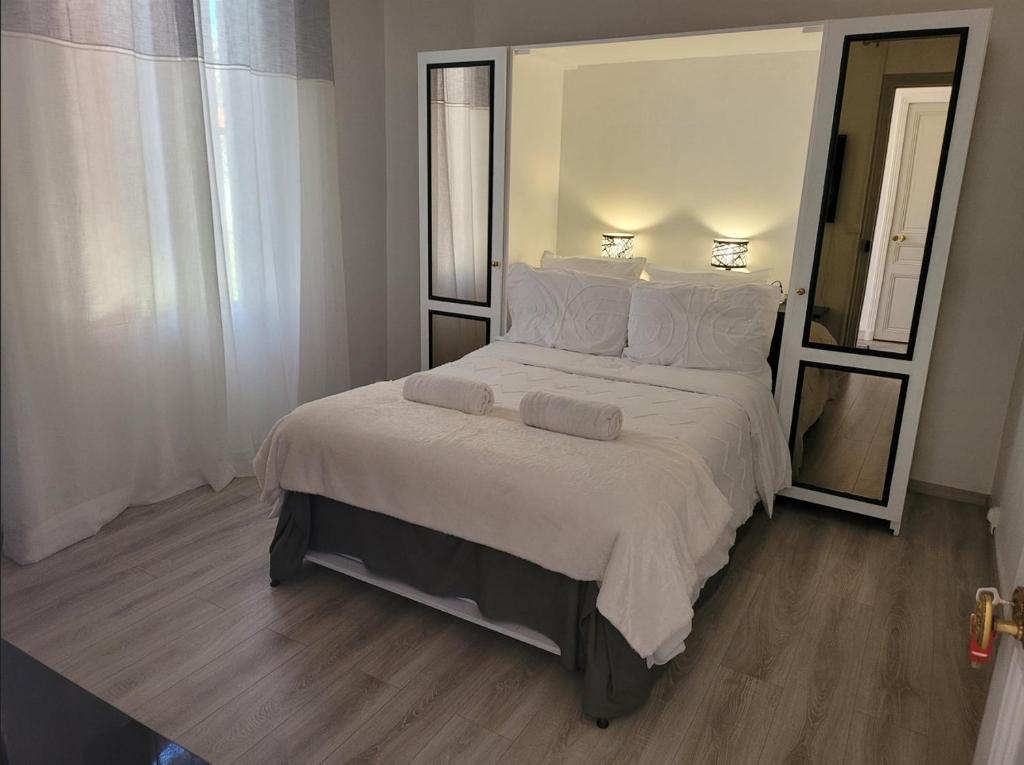 une chambre avec un grand lit avec des draps et des oreillers blancs dans l'établissement 2 Chambres paisibles à La Trinité proche de Nice 15 mn, Monaco 20 mn et l'Italie 30 mn et aussi 2 Studios dans le même établissement, à La Trinité