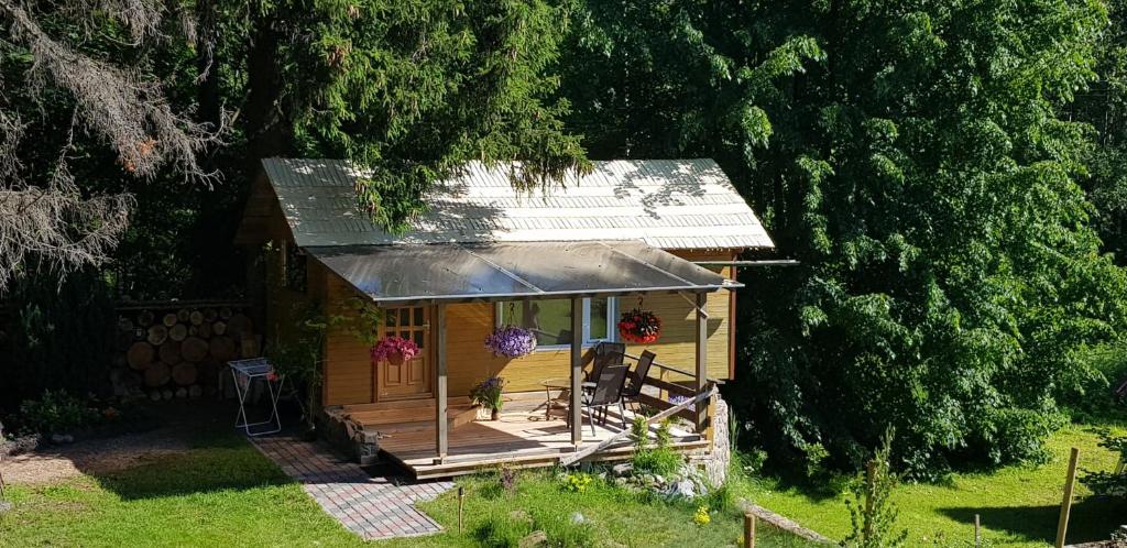 eine kleine Holzhütte mit einer Veranda im Hof in der Unterkunft Atpūta namiņā pie jūras Skujiņas in Lembuži