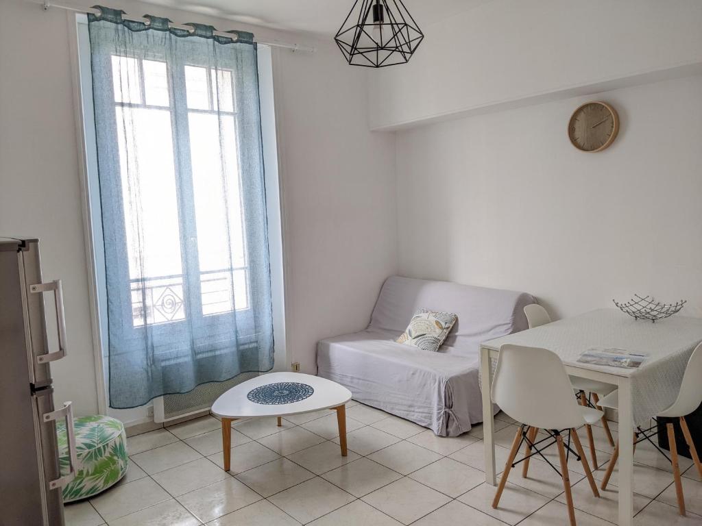 een witte woonkamer met een tafel en een bank bij Fouras - T2 Hyper centre les pieds dans le sable ! in Fouras