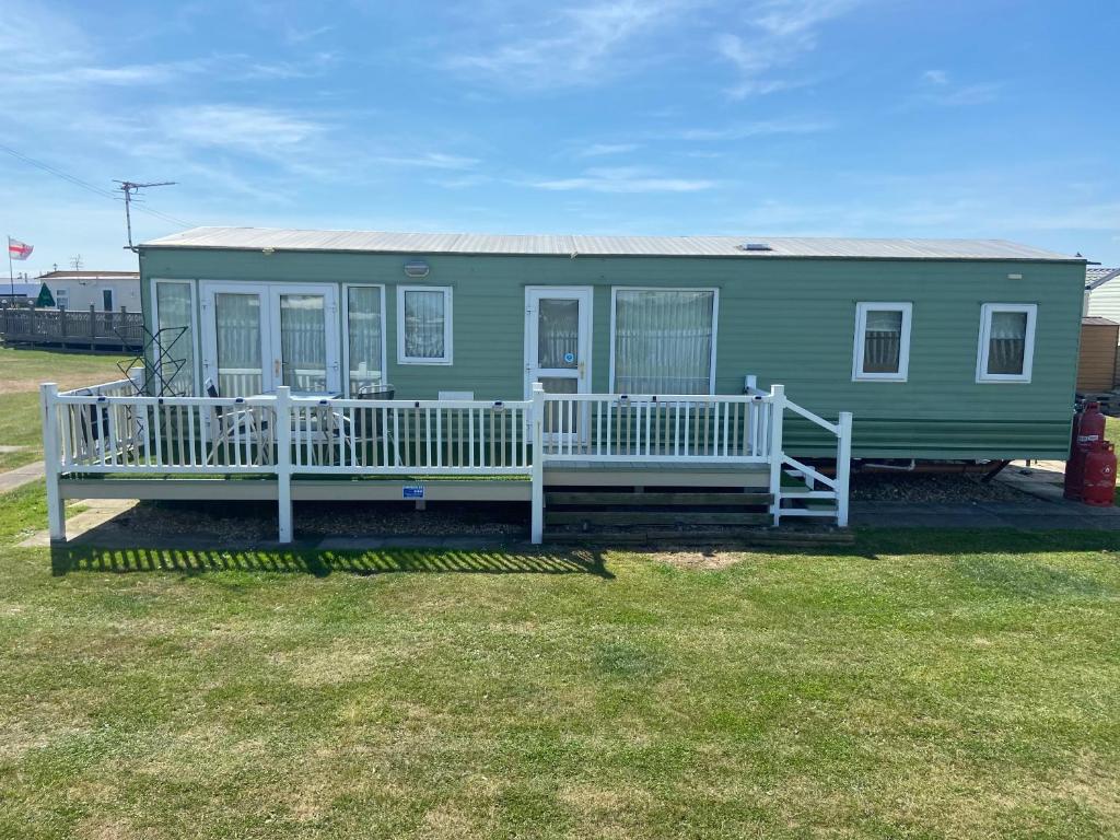 a green house with a porch and a deck at A7 caravan The Chase Ingoldmells in Ingoldmells