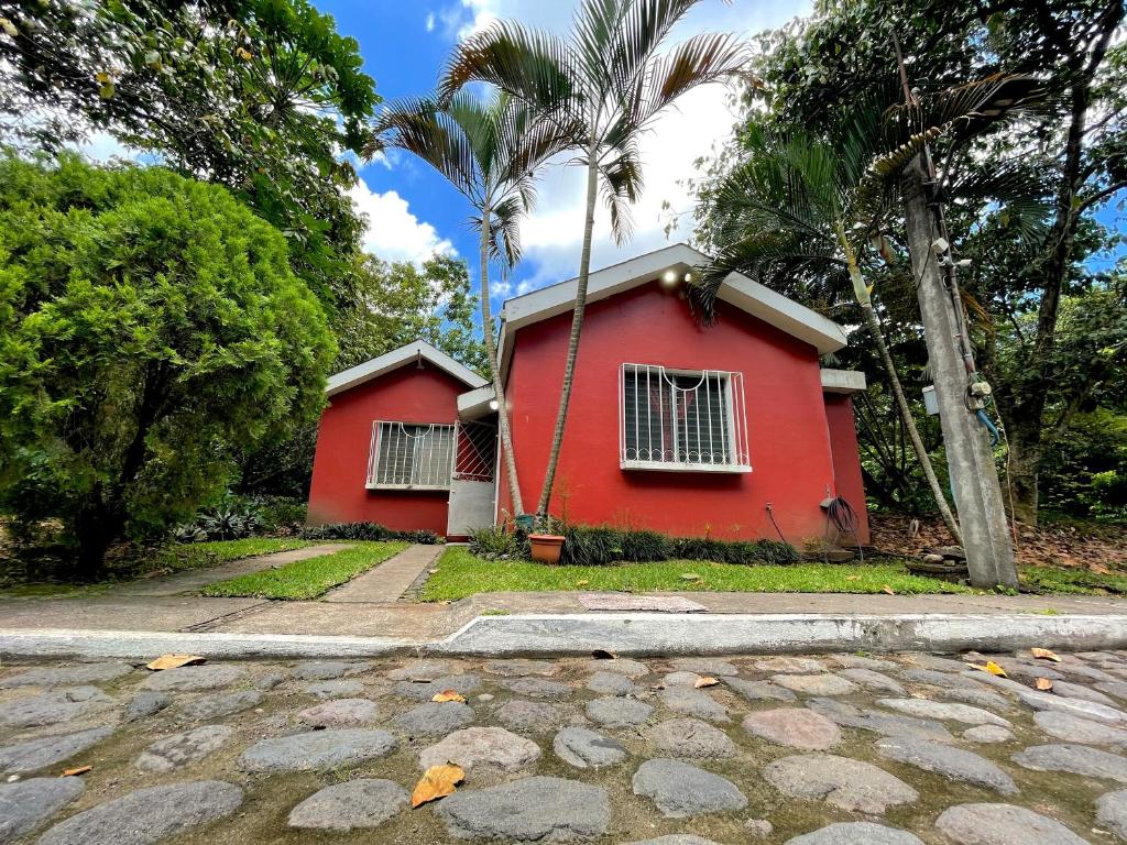 a red house with palm trees next to a street at Casa a 5 minutos de los parques del IRTRA in Pucá