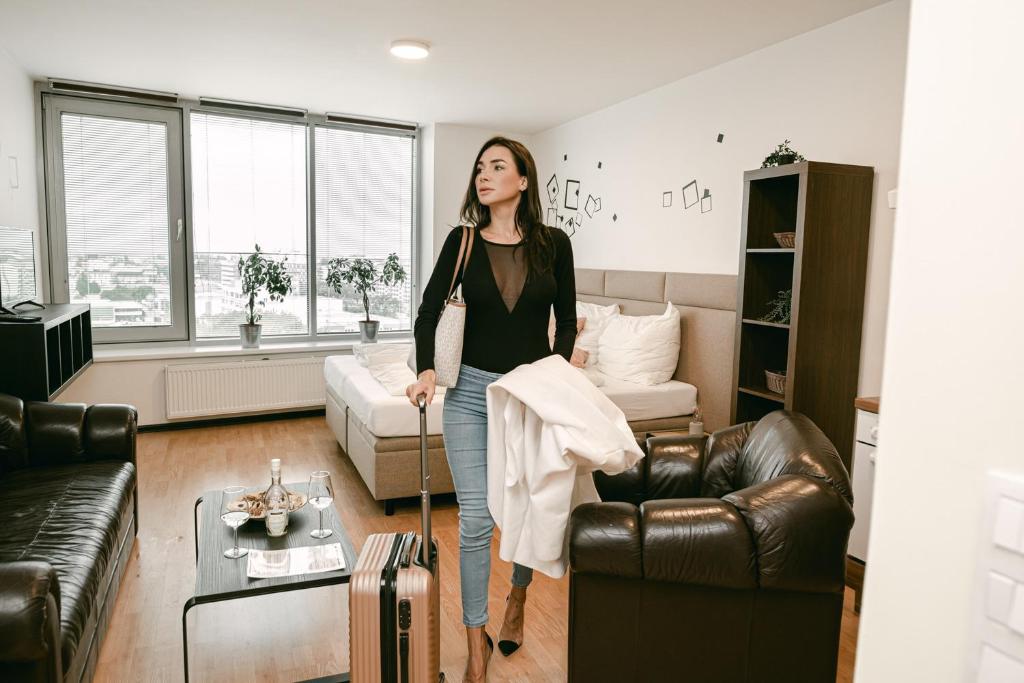 Eine Frau steht in einem Wohnzimmer mit einem Koffer in der Unterkunft Flora Cozy Apartment in Bratislava