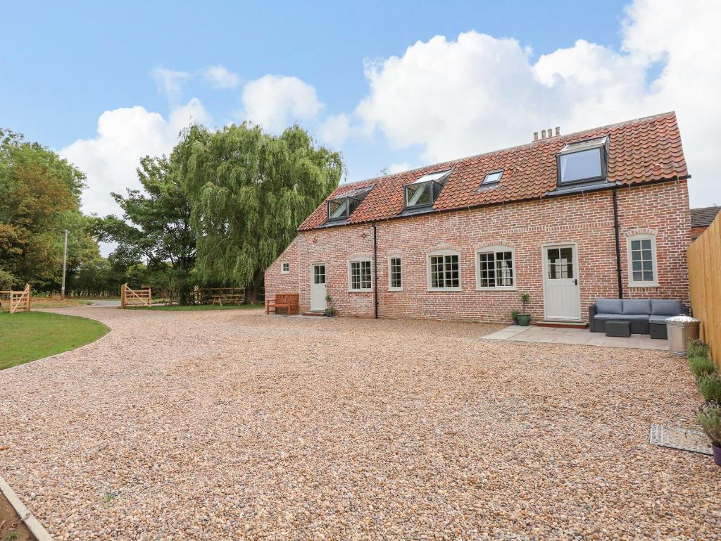 uma casa de tijolos com uma entrada de cascalho em frente em The Stable at Warren House em Market Rasen