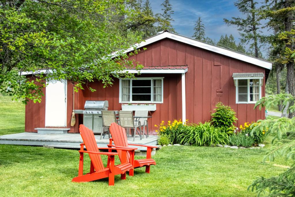 twee rode stoelen voor een rode schuur bij Timbers Resort in Fairmont Hot Springs