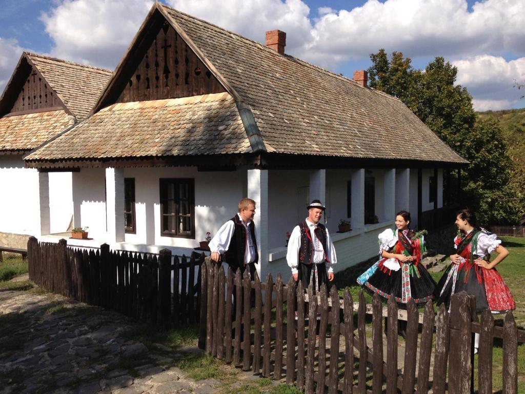 un grupo de personas parados frente a una casa en Hollóköves Vendégházak en Hollókő
