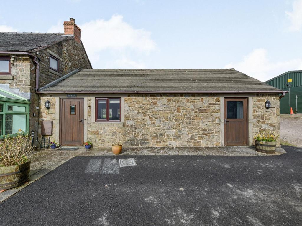 a stone house with a driveway in front of it at Lark's Rise Cottage in Onecote