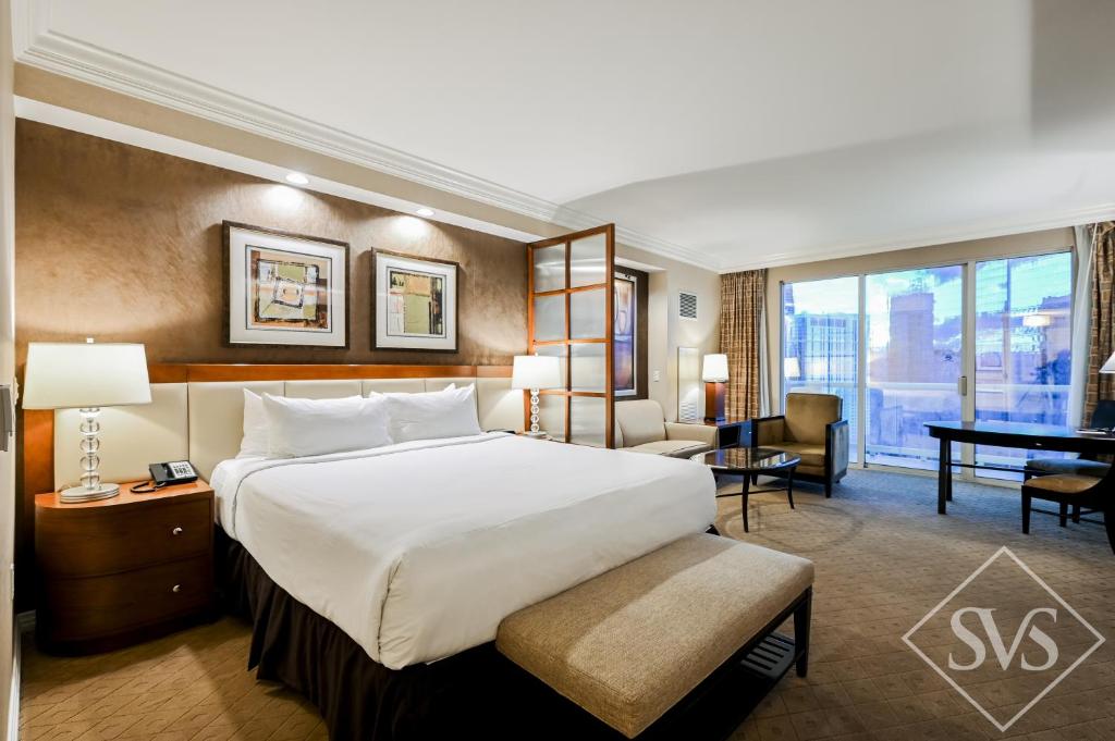 a hotel room with a large bed and a desk at StripViewSuites Penthouse Two-Bedroom Conjoined Suite in Las Vegas
