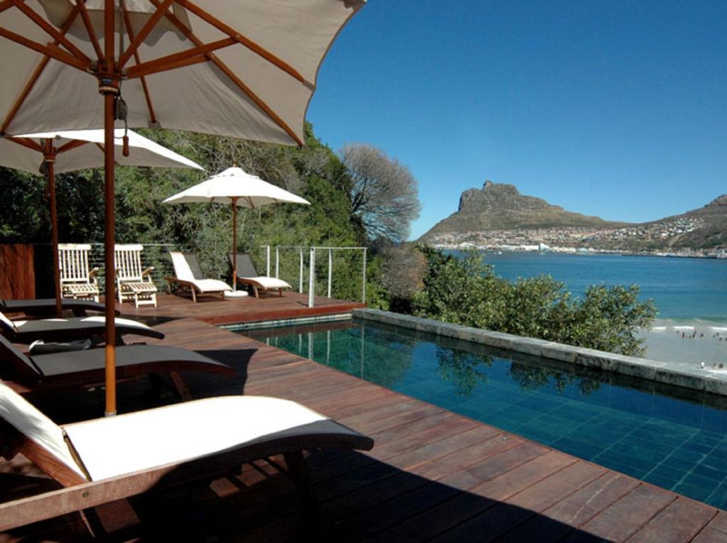 a patio area with chairs, tables and umbrellas at Chapmans Peak Beach Hotel in Hout Bay