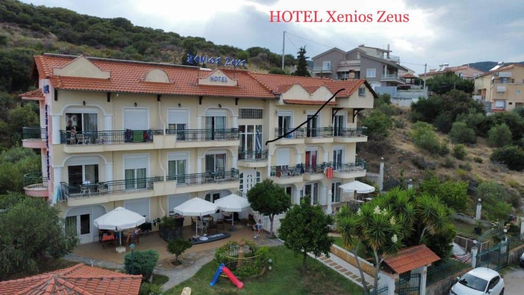 un grand bâtiment avec des parasols blancs devant lui dans l'établissement Xenios Zeus, à Nea Iraklitsa