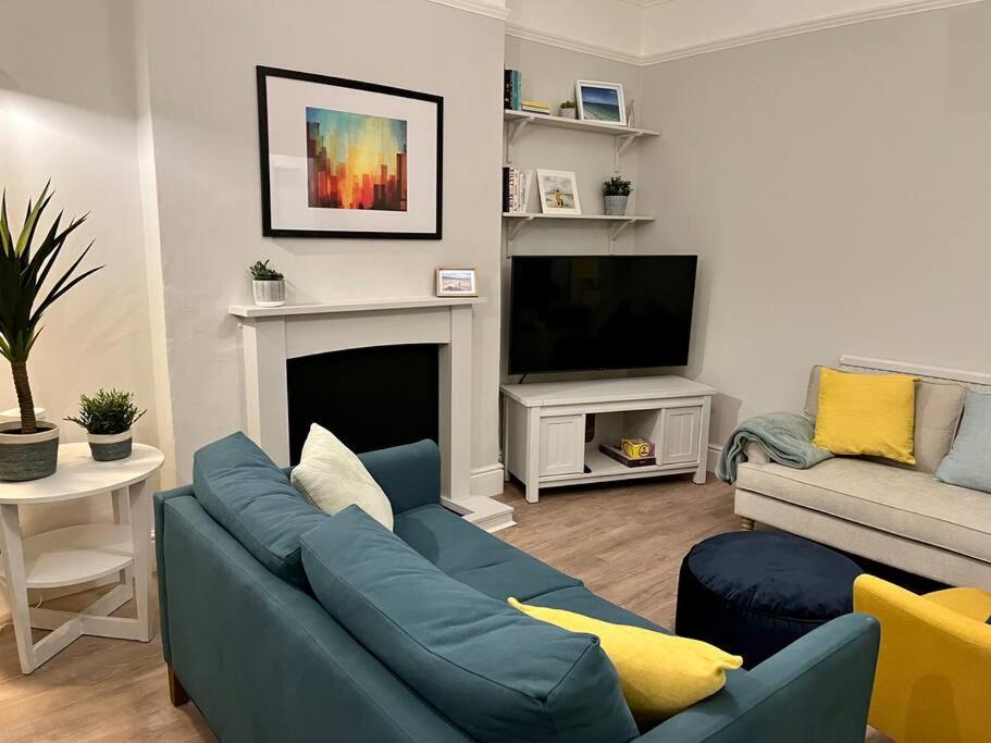 a living room with a blue couch and a tv at Beach home with garden, close to New Forest in Bournemouth