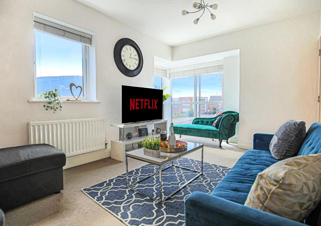 un soggiorno con divano blu e TV di Spacious House - Close to City Centre - Free Parking, Fast Wifi, Smart TVs with Netflix by Yoko Property a Milton Keynes