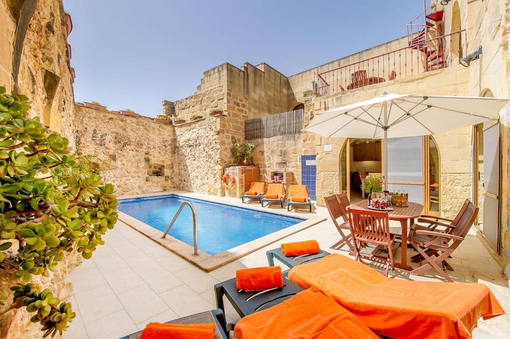 Villa con piscina y mesa con sombrilla en Lellux Holiday Home, en Nadur