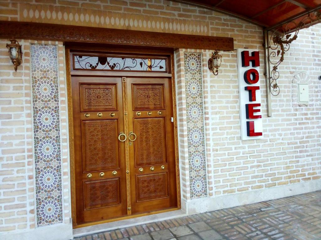 ein Paar Holztüren auf einem Backsteingebäude in der Unterkunft Oybinokh hotel in Buxoro