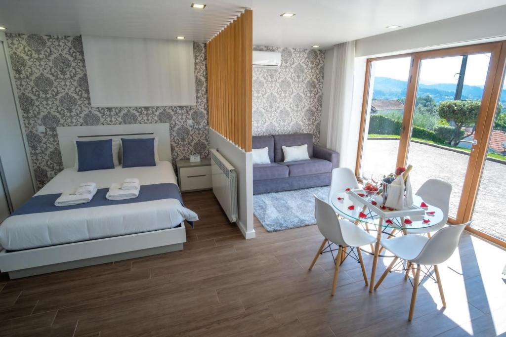 Schlafzimmer mit einem Bett und einem Tisch mit Stühlen in der Unterkunft Villa Tavares Suítes in Arouca