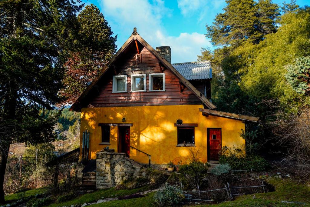 a yellow house with a wooden roof at Los Juncos Patagonian Lake House in San Carlos de Bariloche