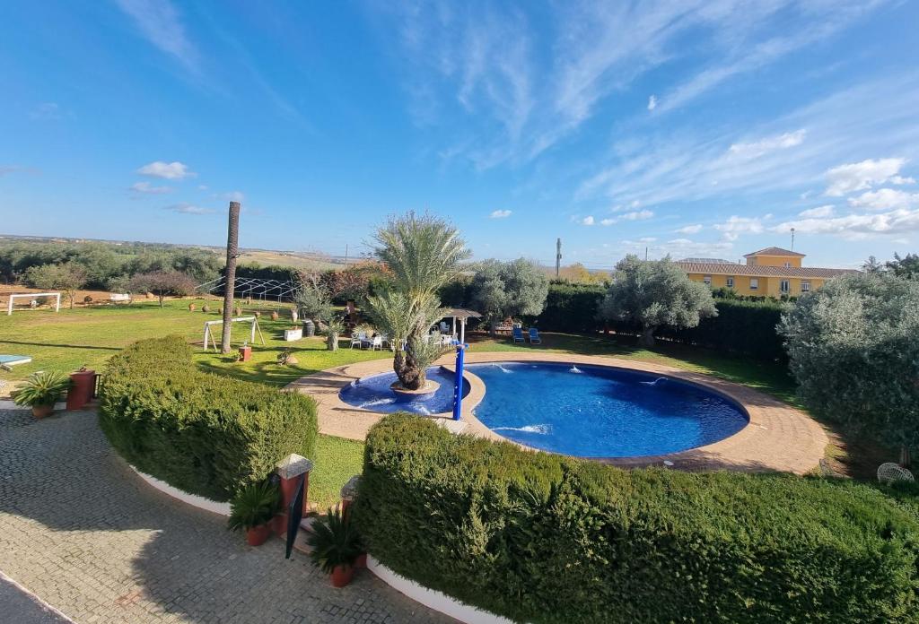 a swimming pool in a garden with bushes at Finca exclusiva (10.000m2) para 10-17 personas in Seville