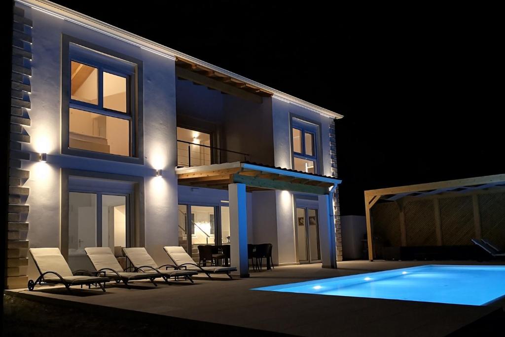 dom z krzesłami i basen w nocy w obiekcie Sunset Sea View Villa 9 w mieście Afionas