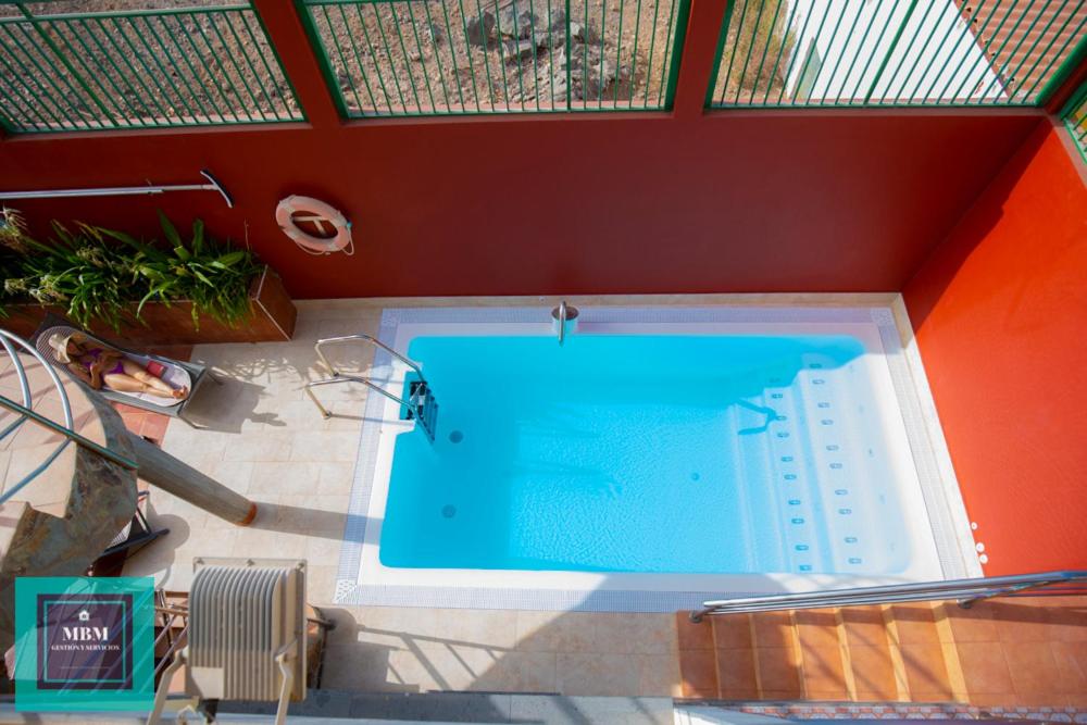 a swimming pool in a room with a red wall at Tita Apartment Montaña La Data in San Bartolomé
