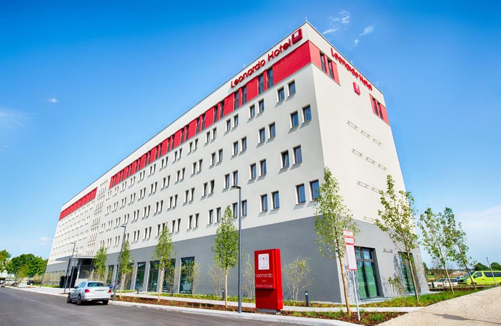a white and red building with a red door at Leonardo Hotel Munich City East in Munich