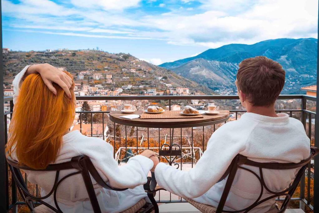 a man and a woman sitting at a table on a balcony at Casa Sofia Apartment in Pimonte