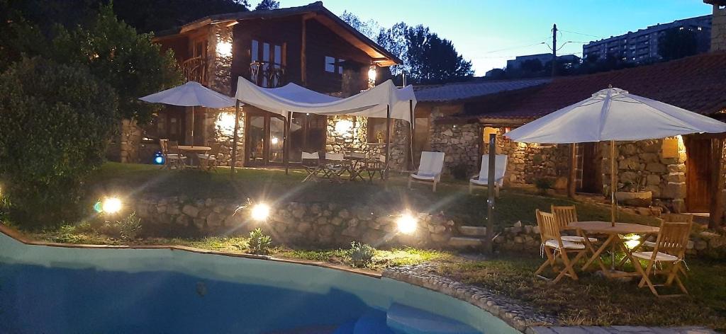 a house with a swimming pool at night with an umbrella at Quinta dos Carvalhos The Wine House Farm in Center of Lamego - Capital of the Douro in Lamego
