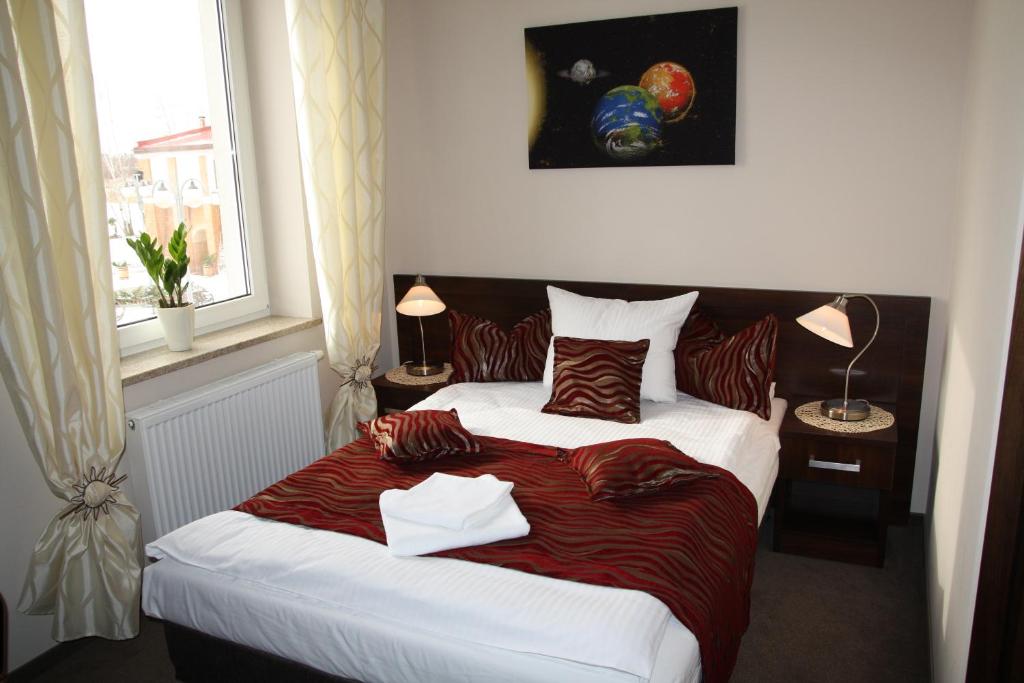 a bedroom with a large bed with a red blanket at Hotel Kosmonauty Wrocław-Airport in Wrocław