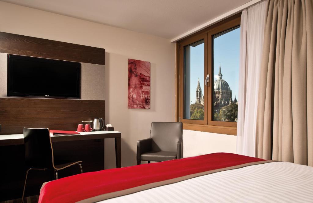 a hotel room with a bed and a desk and a window at Leonardo Hotel Vienna in Vienna