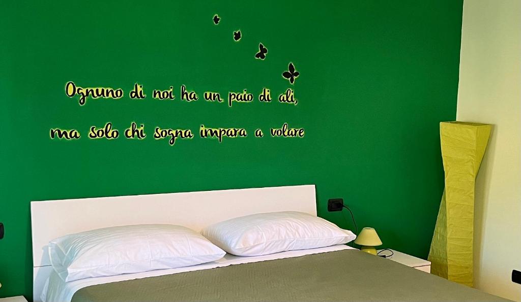1 dormitorio con 1 cama con pared verde en Color House Malpensa B&B, en Cassano Magnago