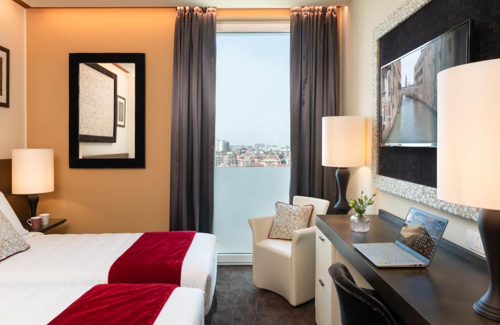 ein Hotelzimmer mit einem Bett und einem Schreibtisch mit einem Laptop in der Unterkunft Leonardo Royal Hotel Venice Mestre in Mestre