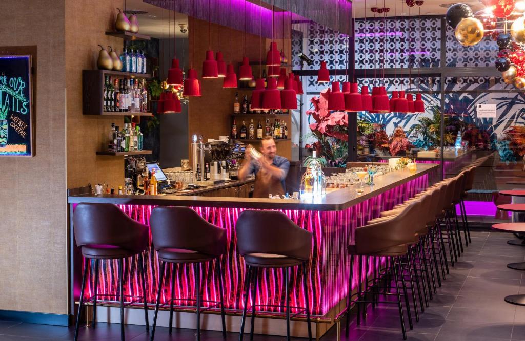 Un bar con sillas negras y luces rojas. en NYX Hotel Madrid by Leonardo Hotels, en Madrid