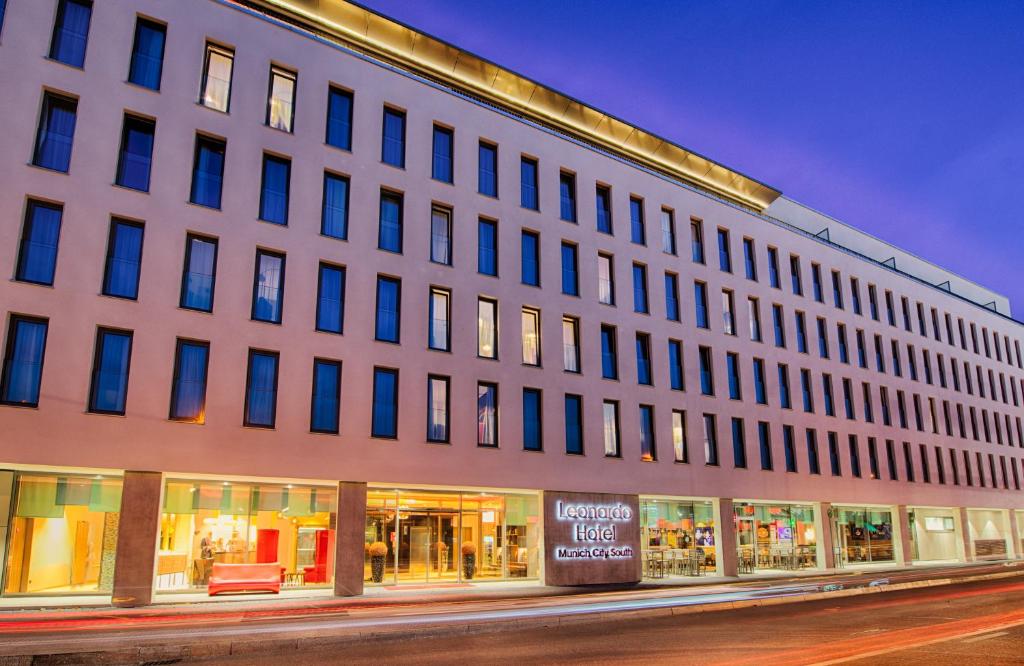 a large white building on a city street at night at Leonardo Hotel Munich City South in Munich