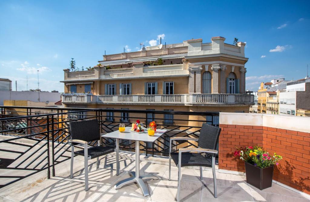 un tavolo e sedie su un balcone con un edificio di Leonardo Boutique Hotel Madrid a Madrid