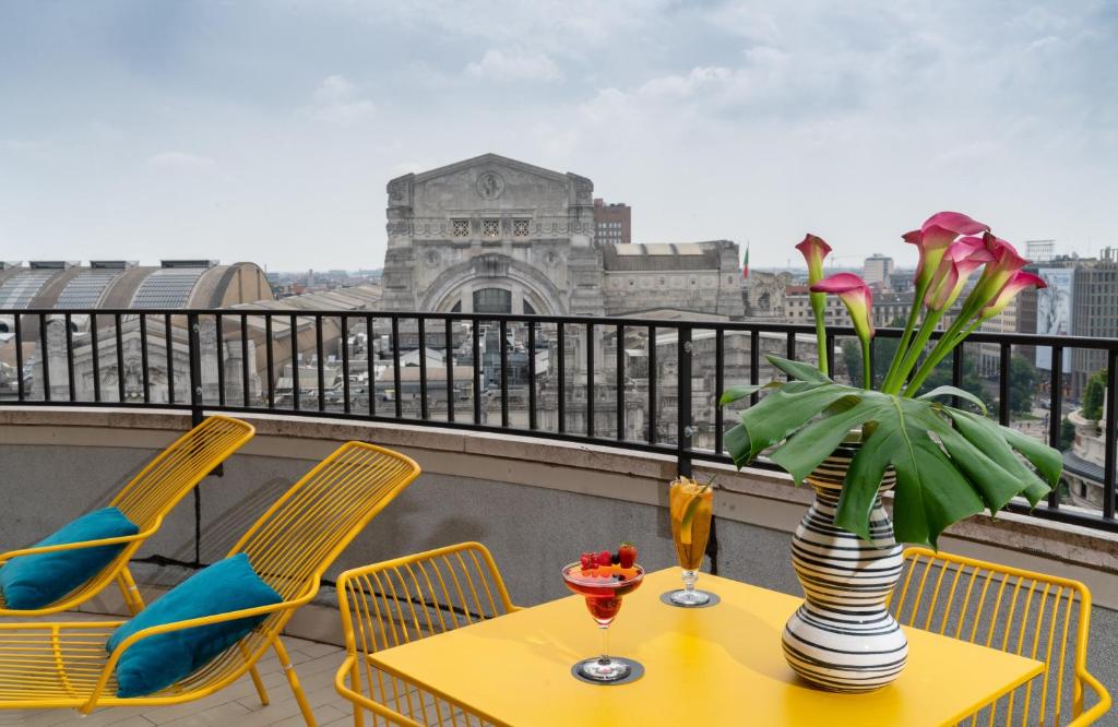 NYX Hotel Milan by Leonardo Hotels في ميلانو: طاولة مع إناء من الزهور على شرفة