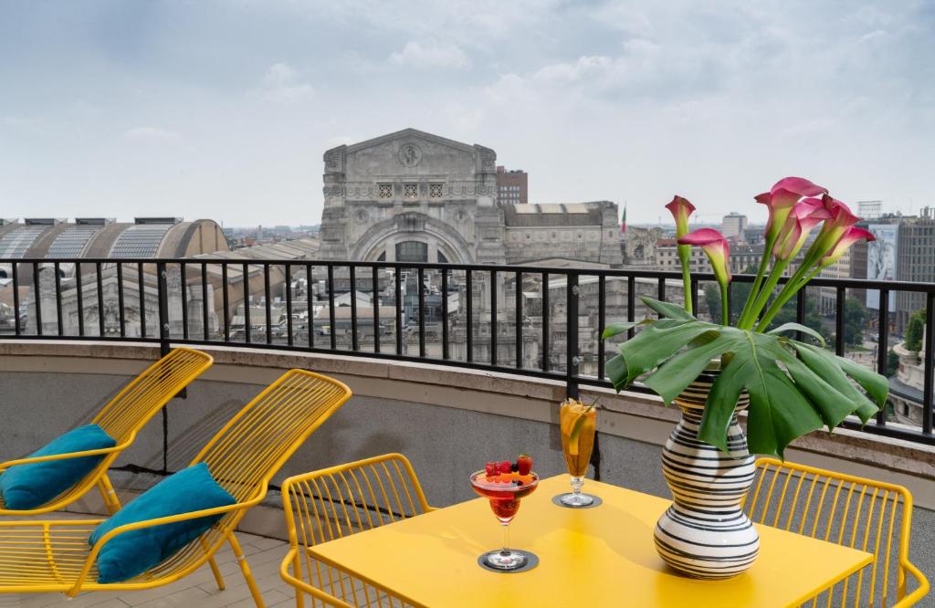 a table with a vase of flowers on a balcony at NYX Hotel Milan by Leonardo Hotels in Milan