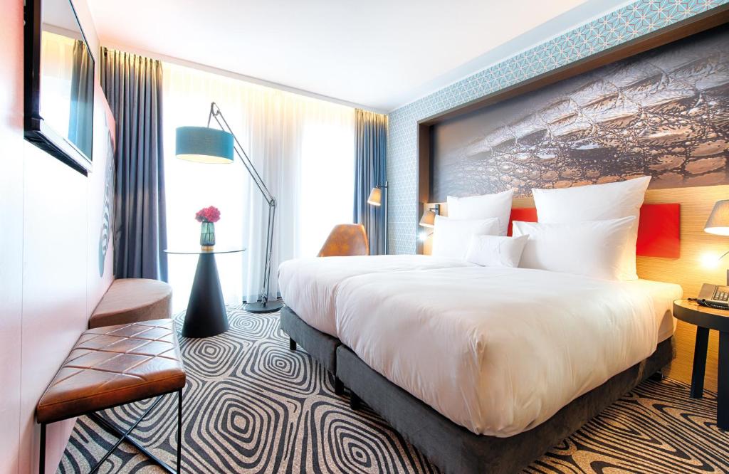 a hotel room with a large bed and a desk at NYX Hotel Munich by Leonardo Hotels in Munich