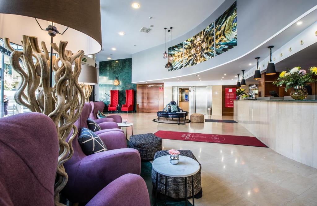 a lobby of a hotel with purple chairs and a table at Leonardo Hotel Barcelona Gran Via in Barcelona