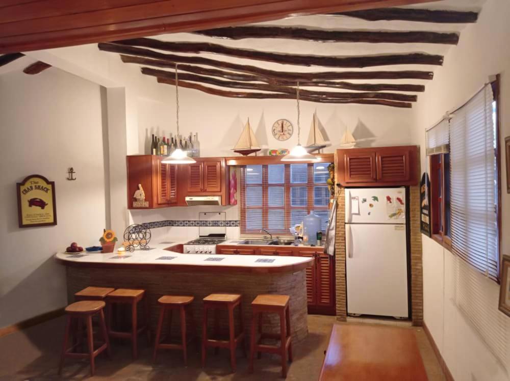 a kitchen with wooden cabinets and a white refrigerator at Villa Vacacionales Los Cayos Con Playa Privada in Boca de Aroa