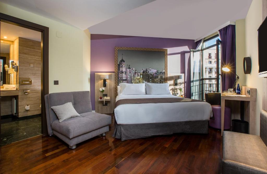 um quarto de hotel com uma cama grande e uma cadeira em Leonardo Hotel Madrid City Center em Madrid