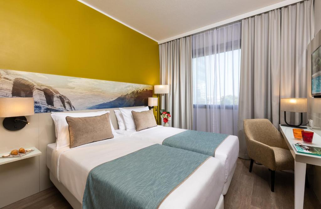 A bed or beds in a room at Leonardo Hotel Verona