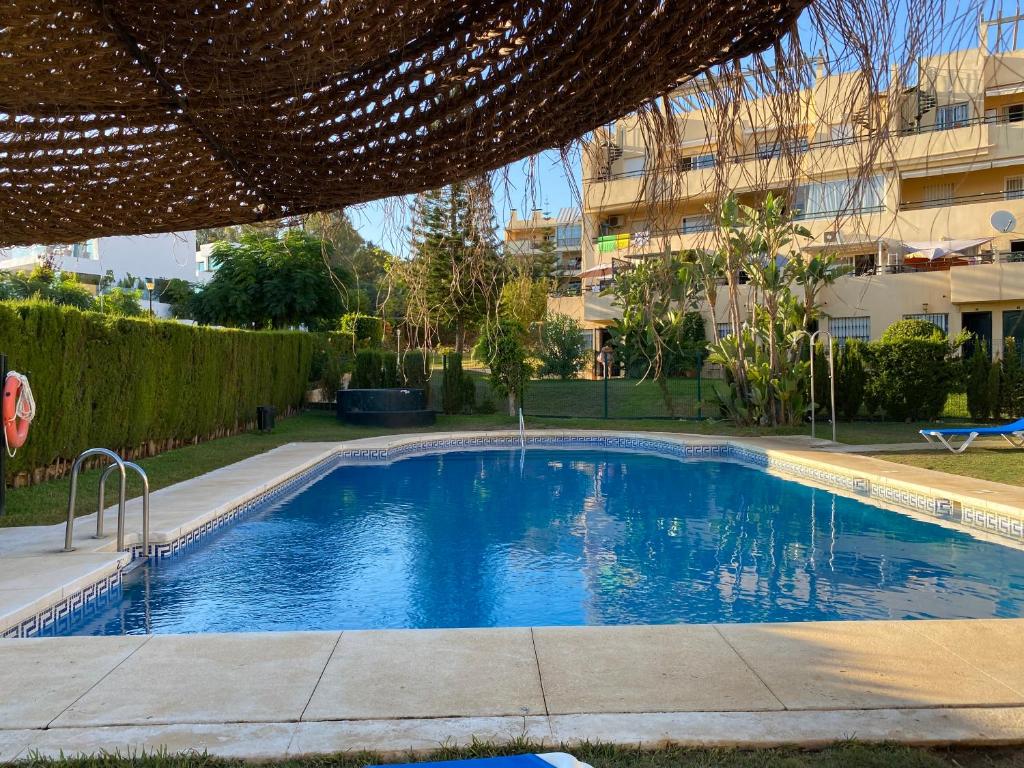 a swimming pool in a yard with a building at Nice ground floor apartment- 2 bedrooms - 450 meters from the beach in Cabopino