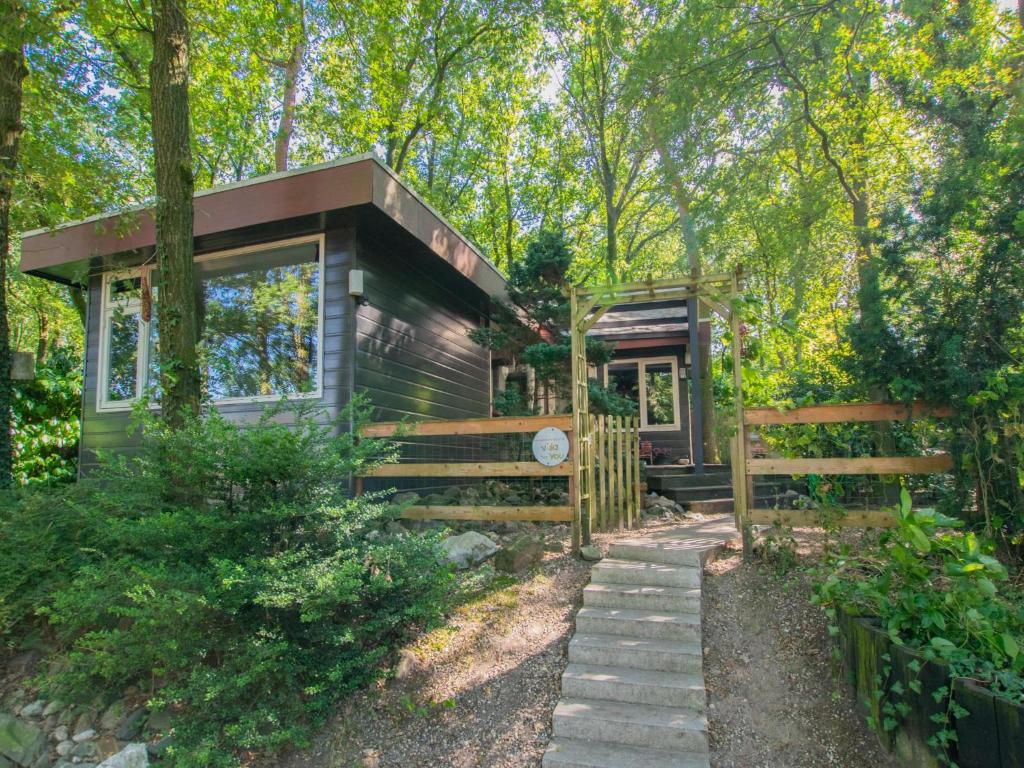 a tiny house in the woods with a wooden fence at Berghuisje in Uden