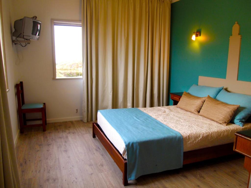 a bedroom with a bed and a window and a television at Hotel Areias Claras in Viana do Castelo