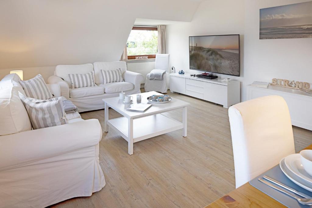 a living room with white furniture and a flat screen tv at Captains Home in List