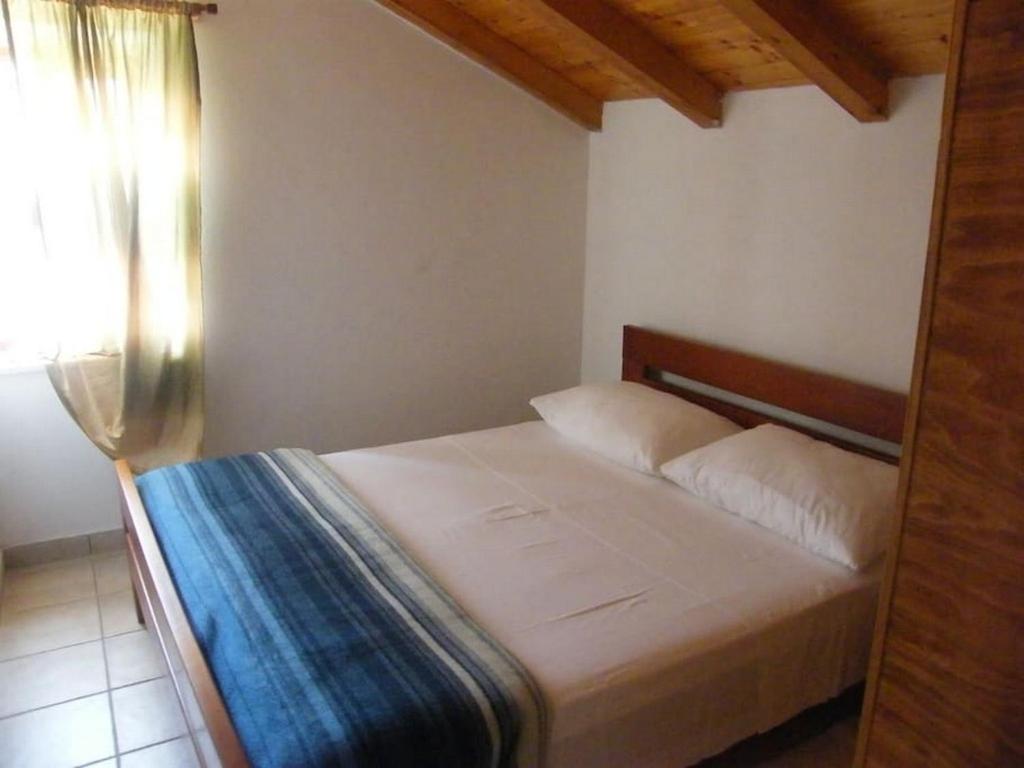 a bedroom with a white bed with a window at Holiday house with a parking space Lumbarda, Korcula - 15165 in Lumbarda