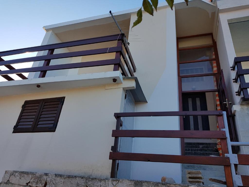 een wit gebouw met een trap en een raam bij Apartments by the sea Cove Koromasna, Zirje - 15166 in Žirje