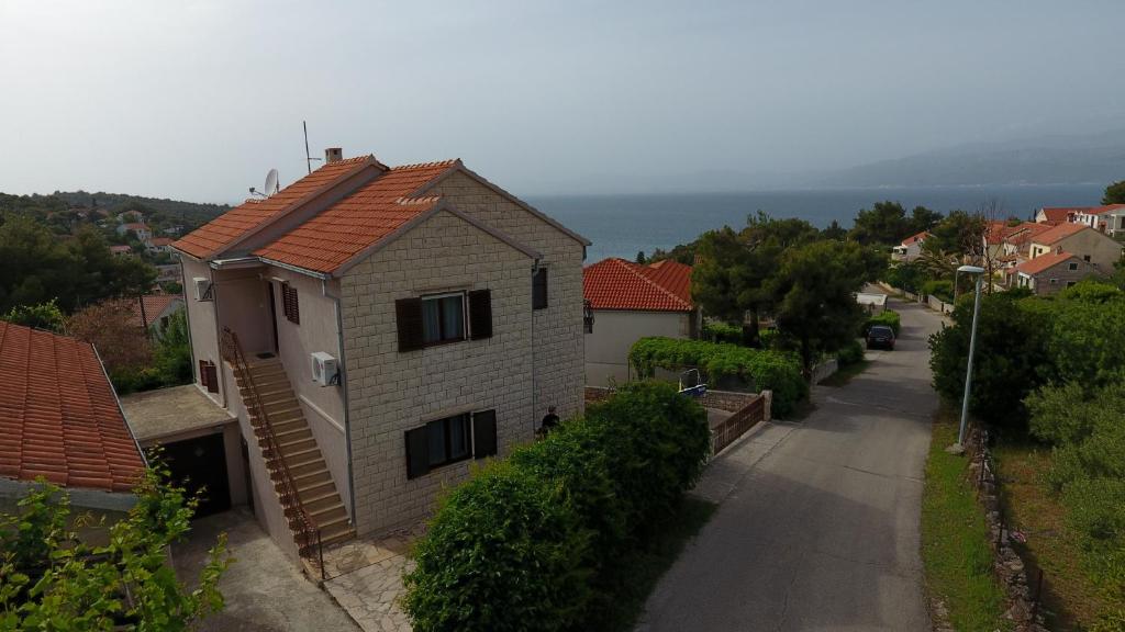 a house on a street with the ocean in the background at Apartments with parking space Splitska, Brac - 15197 in Splitska