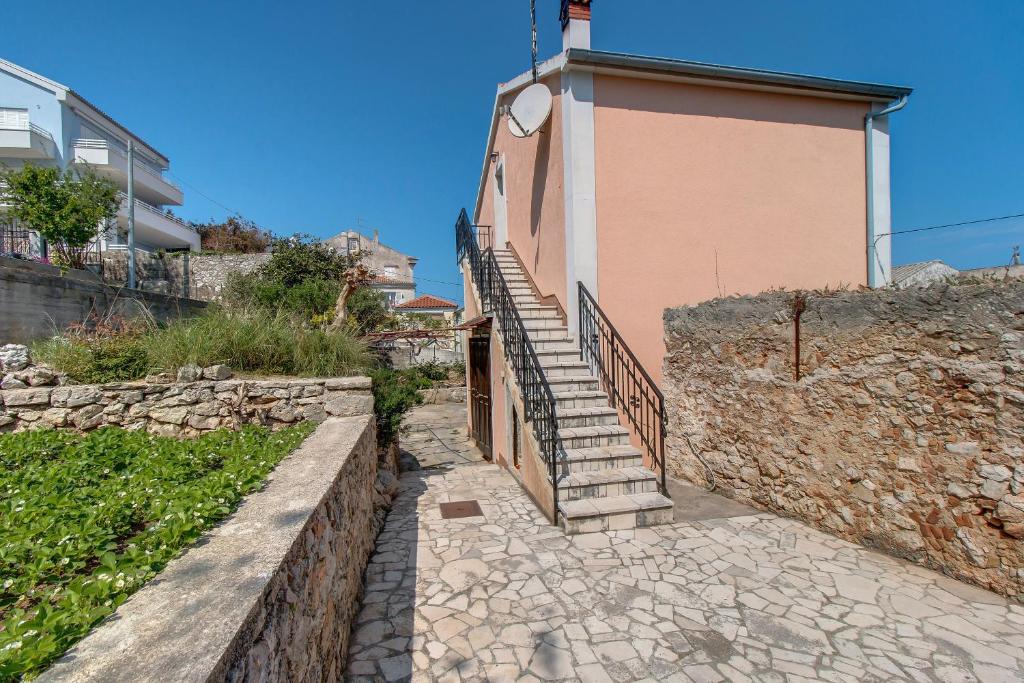 budynek ze schodami obok kamiennej ściany w obiekcie Apartments by the sea Mali Losinj (Losinj) - 15221 w miejscowości Mali Lošinj