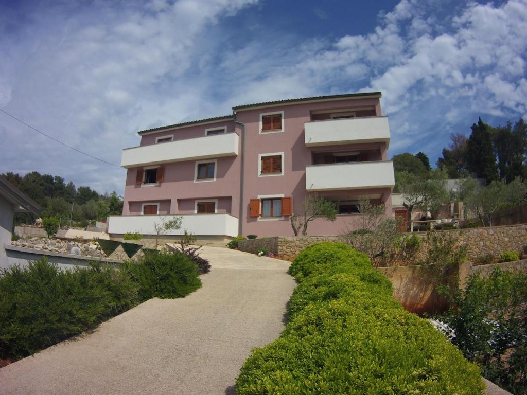 una casa rosa con una pasarela delante de ella en Apartments by the sea Veli Losinj, Losinj - 15229, en Veli Lošinj